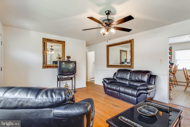 living room featuring wood-type flooring, ceiling fan, and a baseboard heating unit