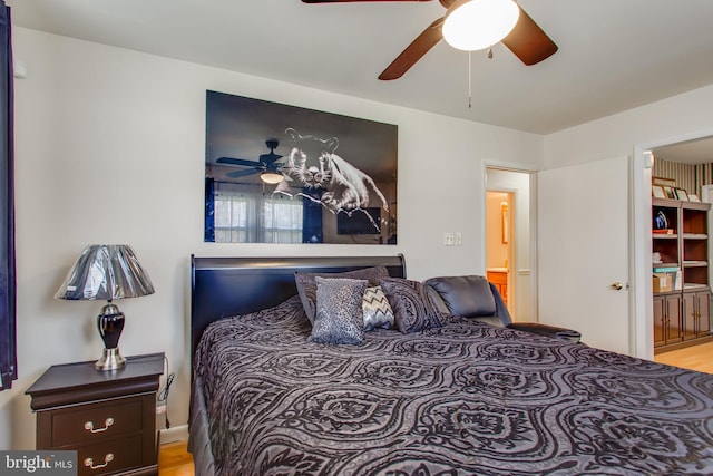 bedroom featuring ceiling fan, light hardwood / wood-style flooring, and connected bathroom