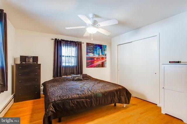 bedroom featuring ceiling fan, a closet, light hardwood / wood-style flooring, and baseboard heating