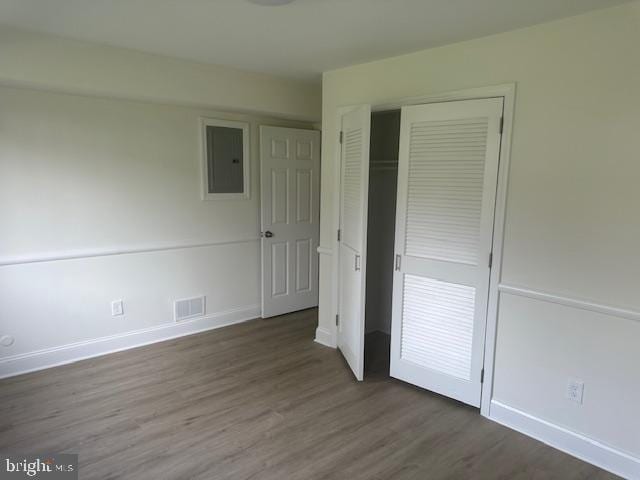 unfurnished bedroom featuring dark hardwood / wood-style floors, a closet, and electric panel