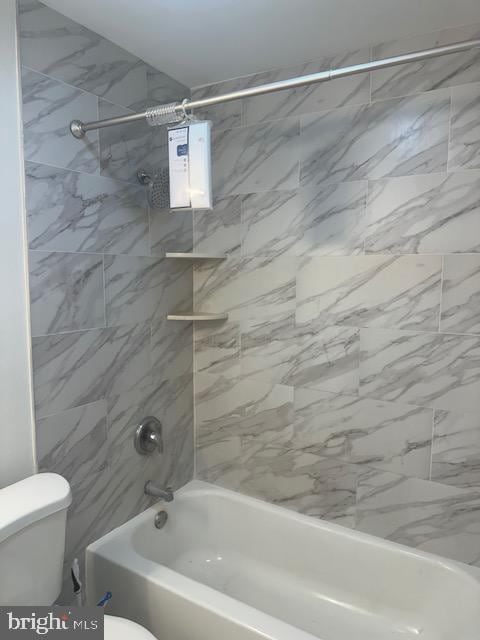 bathroom featuring tiled shower / bath combo and toilet