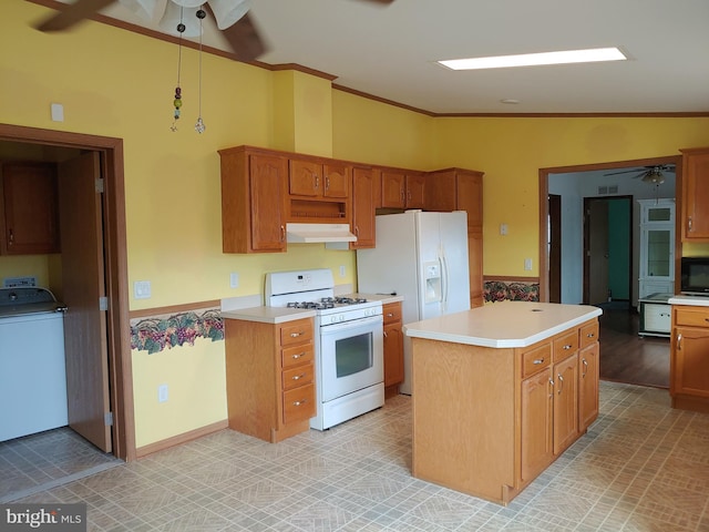 kitchen with white appliances, vaulted ceiling, crown molding, washer / clothes dryer, and a kitchen island