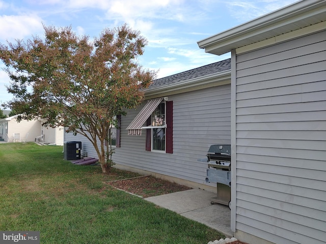 view of side of property featuring central AC unit and a lawn