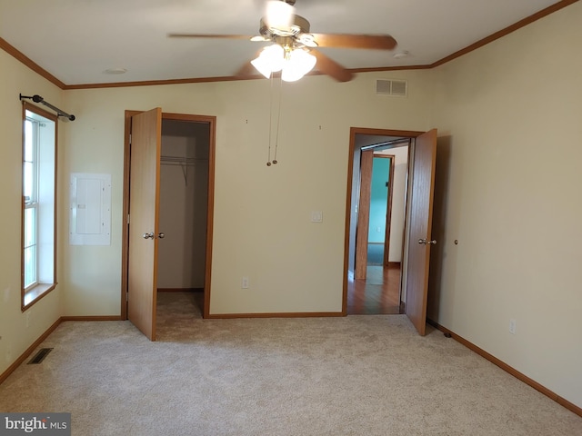 unfurnished bedroom featuring light carpet, ceiling fan, crown molding, electric panel, and a closet