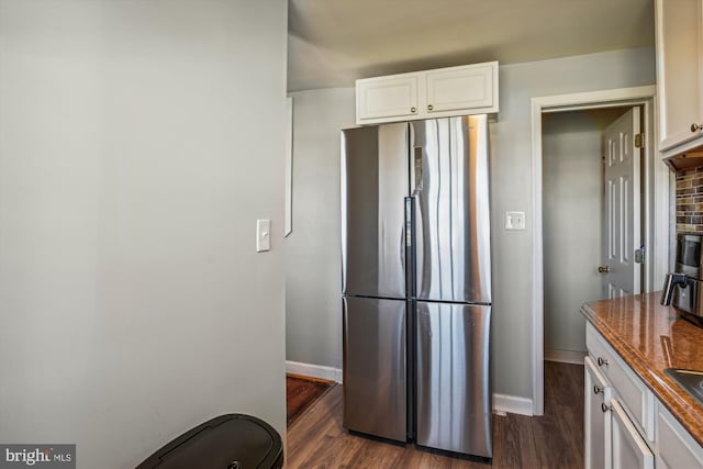 kitchen with stainless steel fridge, white cabinets, and dark wood-type flooring