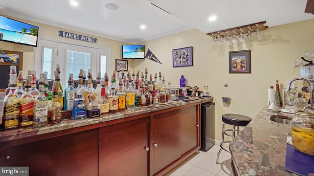 bar with ornamental molding, dark stone countertops, and light tile patterned flooring