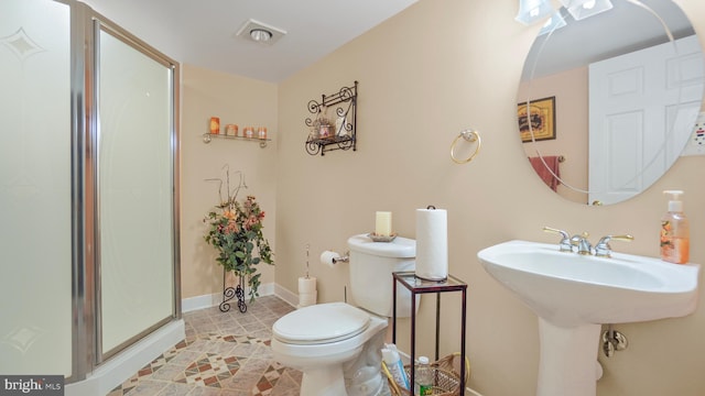 bathroom with a shower with door, toilet, sink, and tile patterned flooring