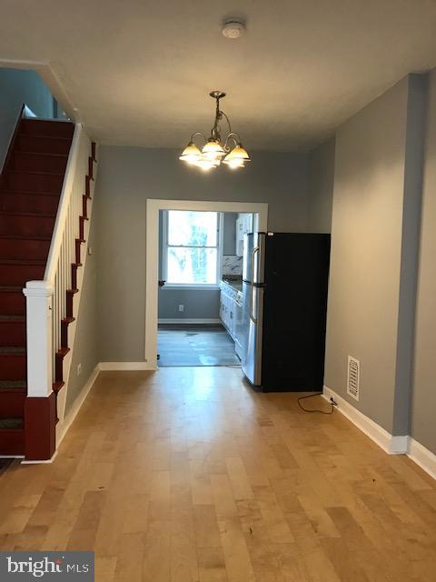 kitchen with white cabinets, stainless steel refrigerator, light hardwood / wood-style flooring, and a chandelier