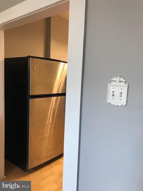 interior details with light wood-type flooring and stainless steel fridge