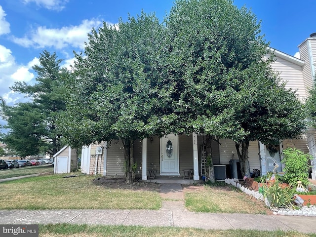 obstructed view of property with a garage, an outdoor structure, a front lawn, and covered porch