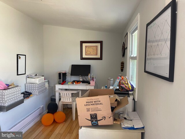 office with light hardwood / wood-style flooring, a baseboard heating unit, and lofted ceiling