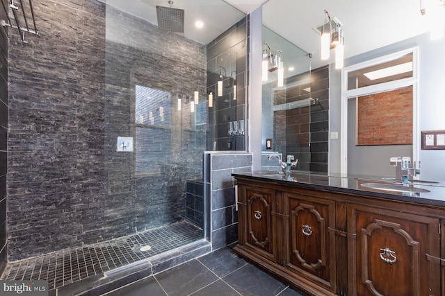 bathroom with a tile shower and vanity