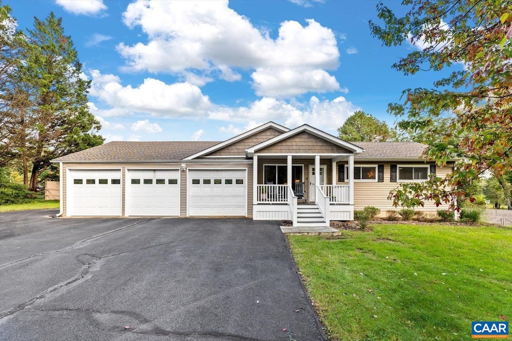 view of front of property featuring a front yard, a garage, and a porch