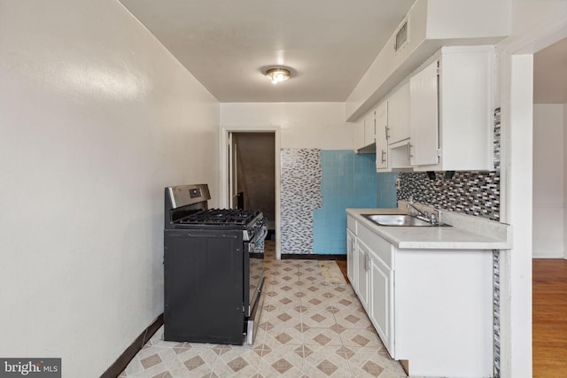 kitchen featuring black gas stove, light wood-type flooring, sink, and white cabinets