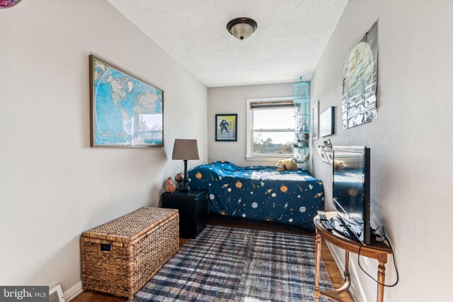 bedroom featuring a textured ceiling and dark hardwood / wood-style floors