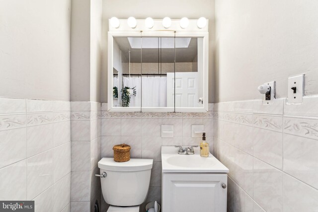 bathroom with tile walls, vanity, and toilet