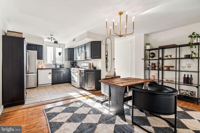 kitchen featuring an inviting chandelier, light hardwood / wood-style flooring, gray cabinetry, and white appliances