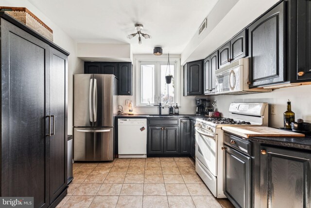 kitchen with white appliances, light tile patterned floors, and sink