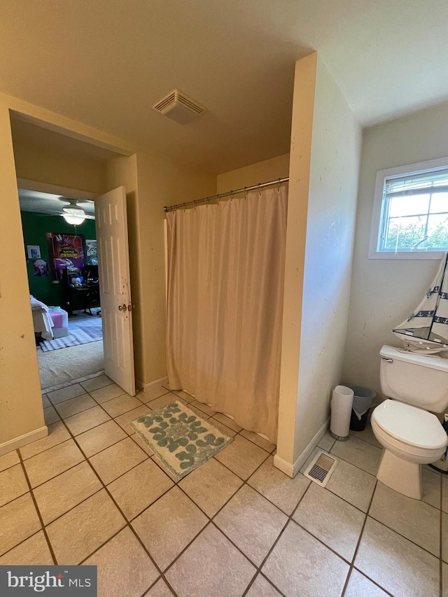 bathroom with toilet, a shower with shower curtain, and tile patterned flooring