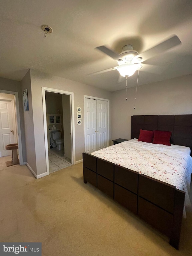 bedroom with ceiling fan, light carpet, and ensuite bath