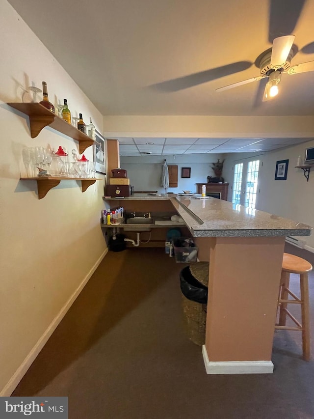 kitchen featuring kitchen peninsula, a kitchen bar, and ceiling fan