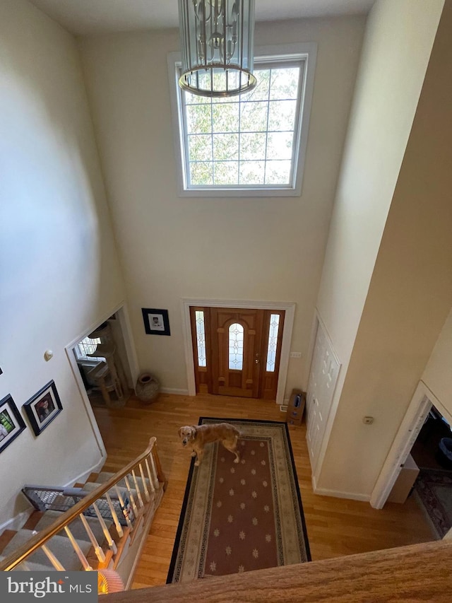 entryway with light hardwood / wood-style floors, a high ceiling, and an inviting chandelier