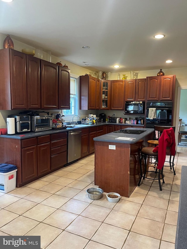 kitchen with sink, black appliances, a center island, a kitchen bar, and light tile patterned flooring