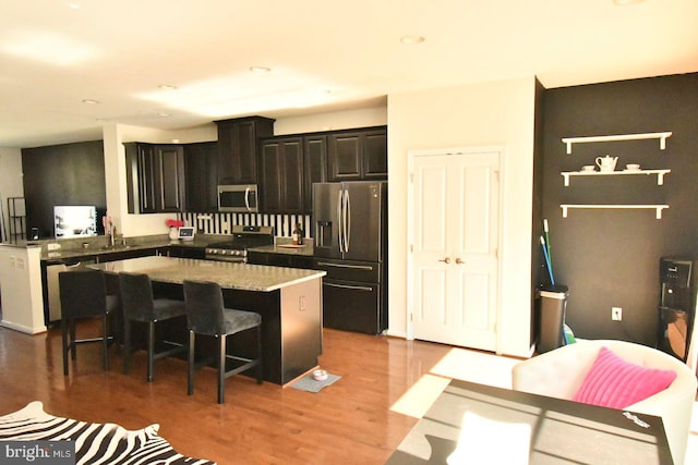 kitchen featuring stainless steel appliances, sink, hardwood / wood-style floors, a center island, and a kitchen bar