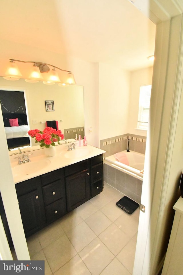 bathroom featuring vanity, a relaxing tiled tub, and tile patterned flooring