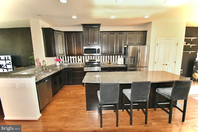 kitchen featuring sink, kitchen peninsula, stainless steel appliances, and light hardwood / wood-style floors