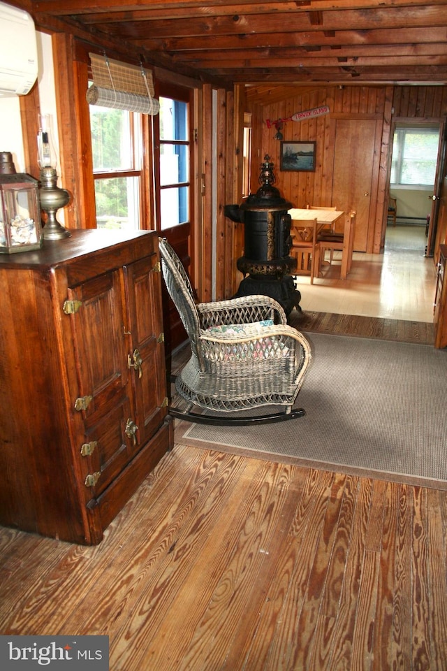 sitting room with an AC wall unit, wooden walls, and light hardwood / wood-style flooring