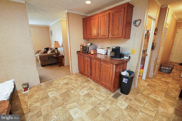 kitchen featuring ornamental molding, a textured ceiling, and light colored carpet