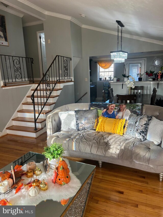 living room featuring crown molding, hardwood / wood-style flooring, a chandelier, and vaulted ceiling