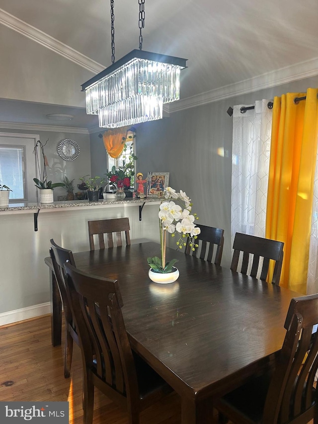 dining room featuring hardwood / wood-style flooring, ornamental molding, and an inviting chandelier