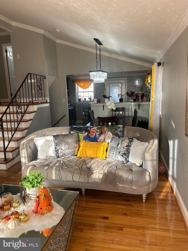 living room with an inviting chandelier, ornamental molding, hardwood / wood-style floors, and lofted ceiling