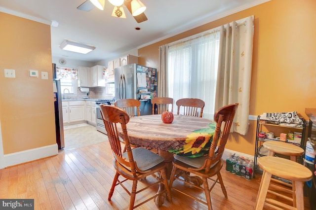 dining area featuring crown molding, light hardwood / wood-style floors, sink, and ceiling fan