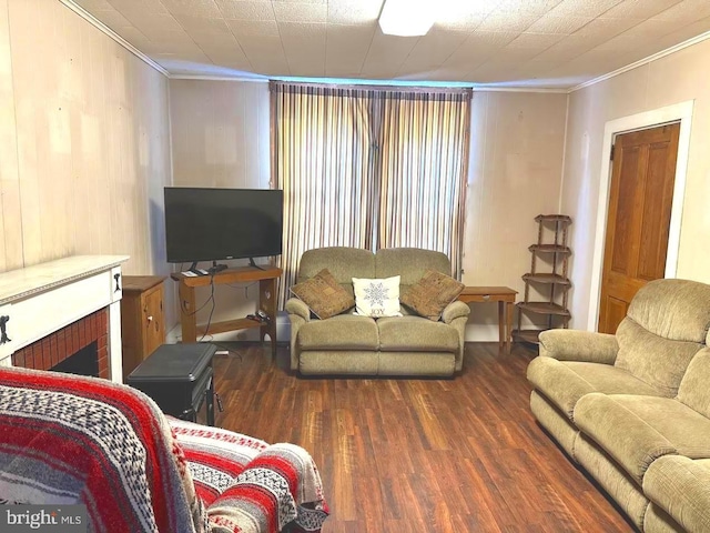 living room with dark wood-type flooring, a brick fireplace, and ornamental molding