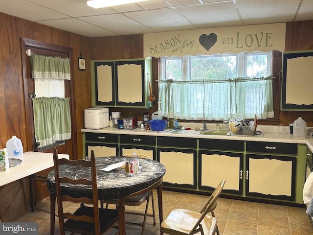 kitchen featuring wood walls, sink, and a drop ceiling