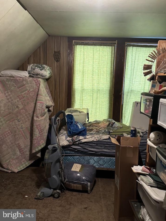 bedroom featuring wood walls and lofted ceiling