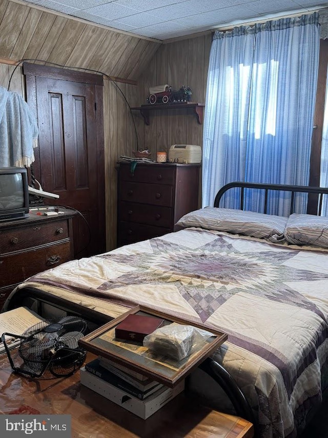 bedroom with lofted ceiling and wooden walls