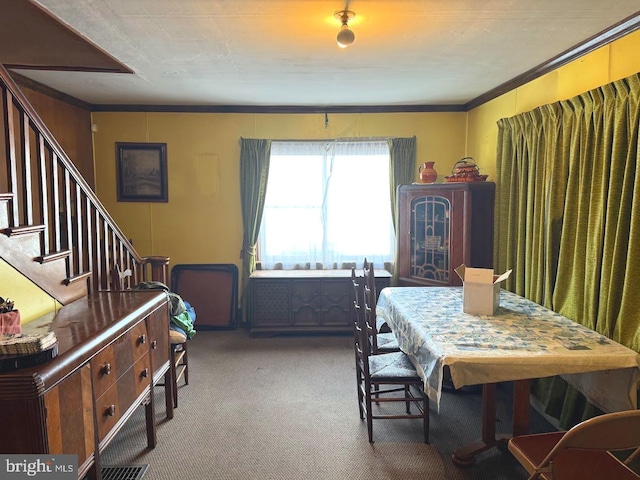 carpeted dining room with crown molding