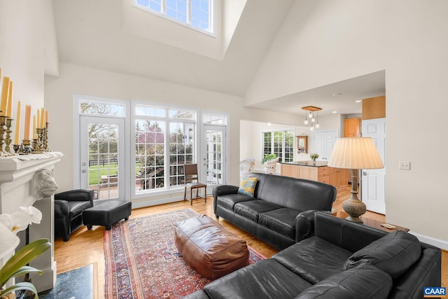 living area featuring a skylight, high vaulted ceiling, and light wood-style floors