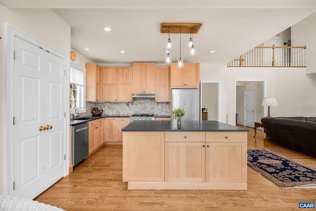 kitchen featuring stainless steel appliances, under cabinet range hood, dark countertops, light brown cabinets, and light wood-style flooring