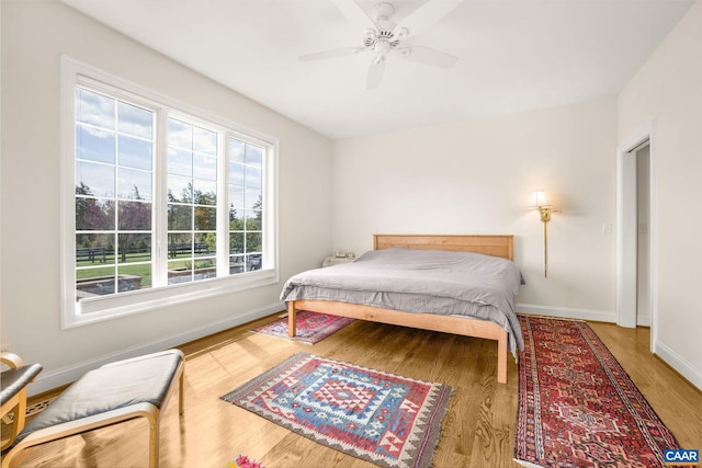 bedroom with baseboards, a ceiling fan, and wood finished floors