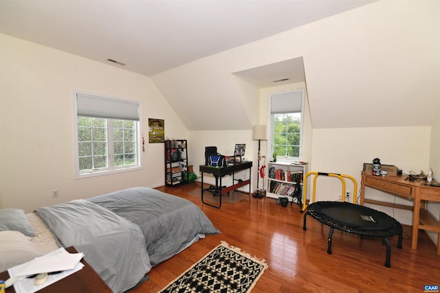 bedroom with visible vents, vaulted ceiling, and wood finished floors