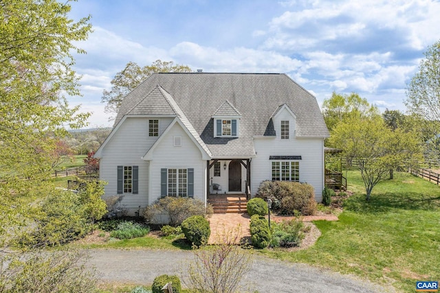 cape cod home with roof with shingles, a front yard, and fence