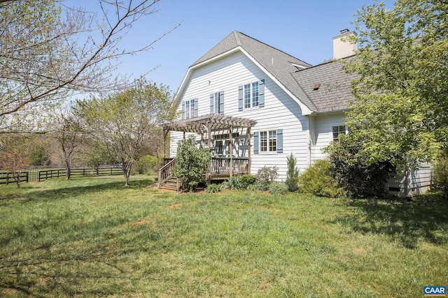 rear view of house featuring roof with shingles, a pergola, fence, a wooden deck, and a yard