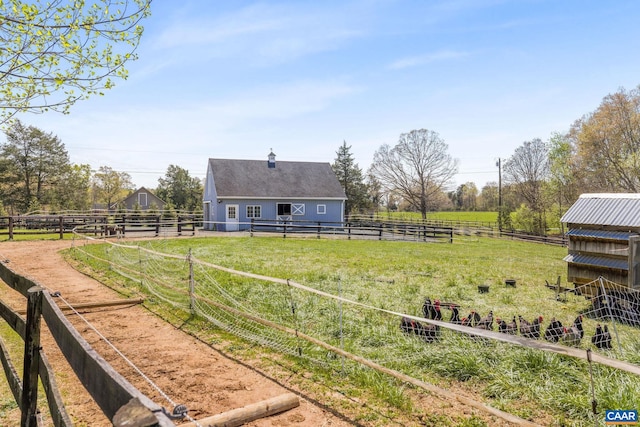 view of yard featuring a rural view, an outbuilding, and an exterior structure