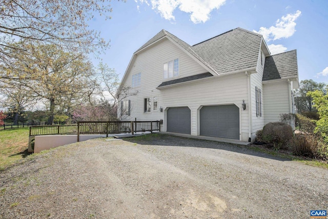 view of side of home featuring a shingled roof, driveway, and a garage