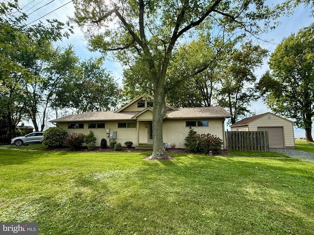 view of front of house with a garage, an outbuilding, and a front lawn